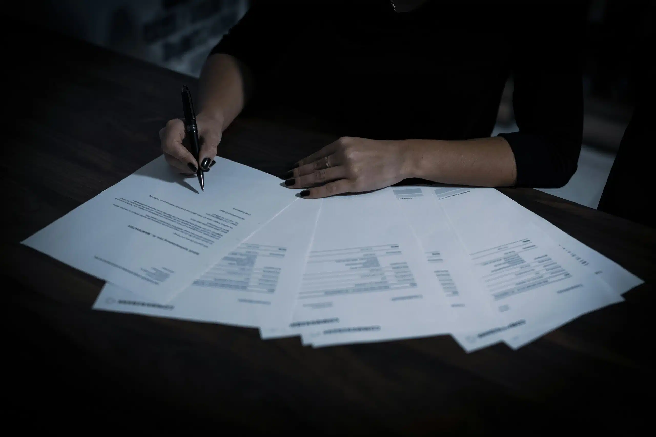 A person signing multiple documents, symbolizing the importance of carefully reviewing rental agreements and understanding tent rental policies.