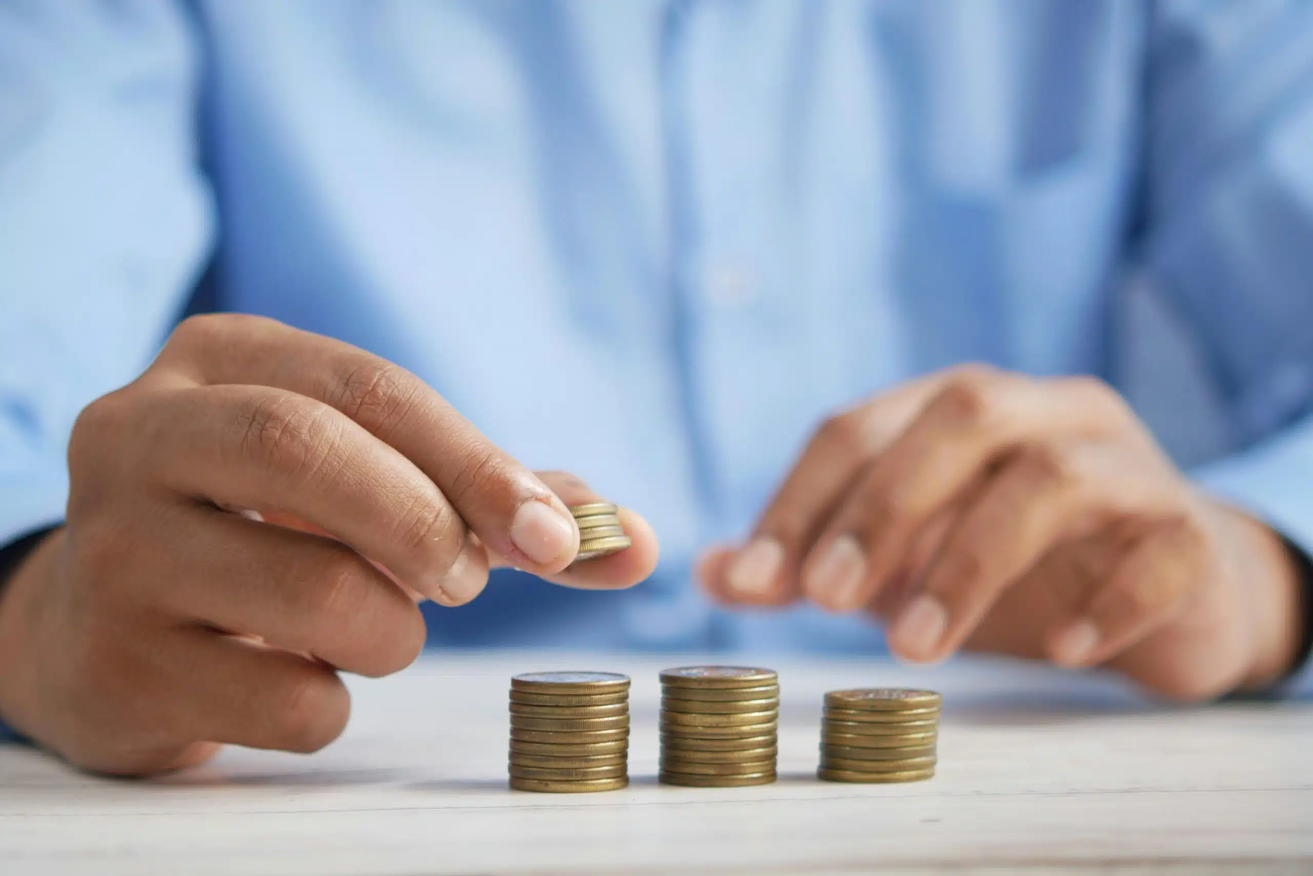 A person stacking coins on a table, symbolizing the analysis of cost factors and budgeting considerations for portable tent rentals.