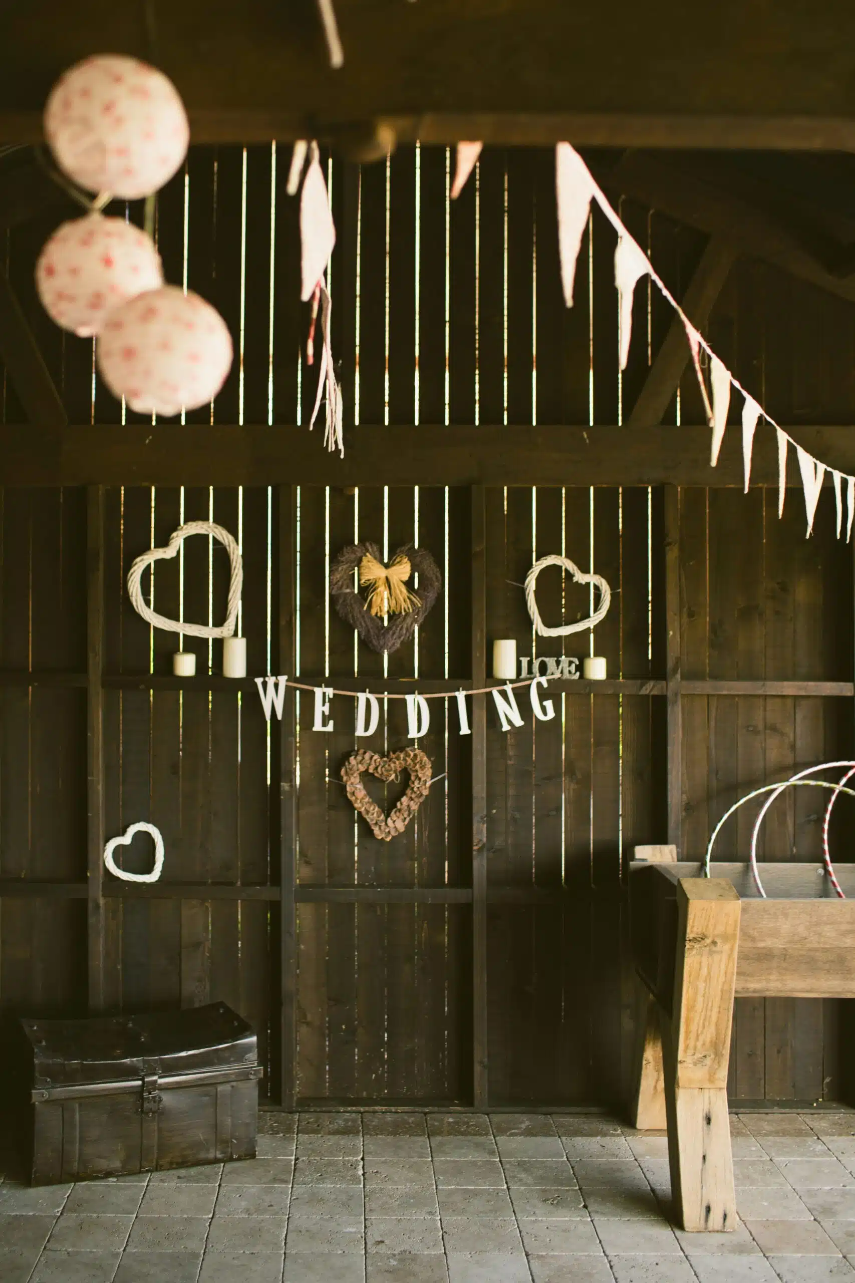 Rustic wooden backdrop decorated with heart-shaped wreaths, candles, and bunting, creating a charming vintage setting for a cozy wedding celebration.