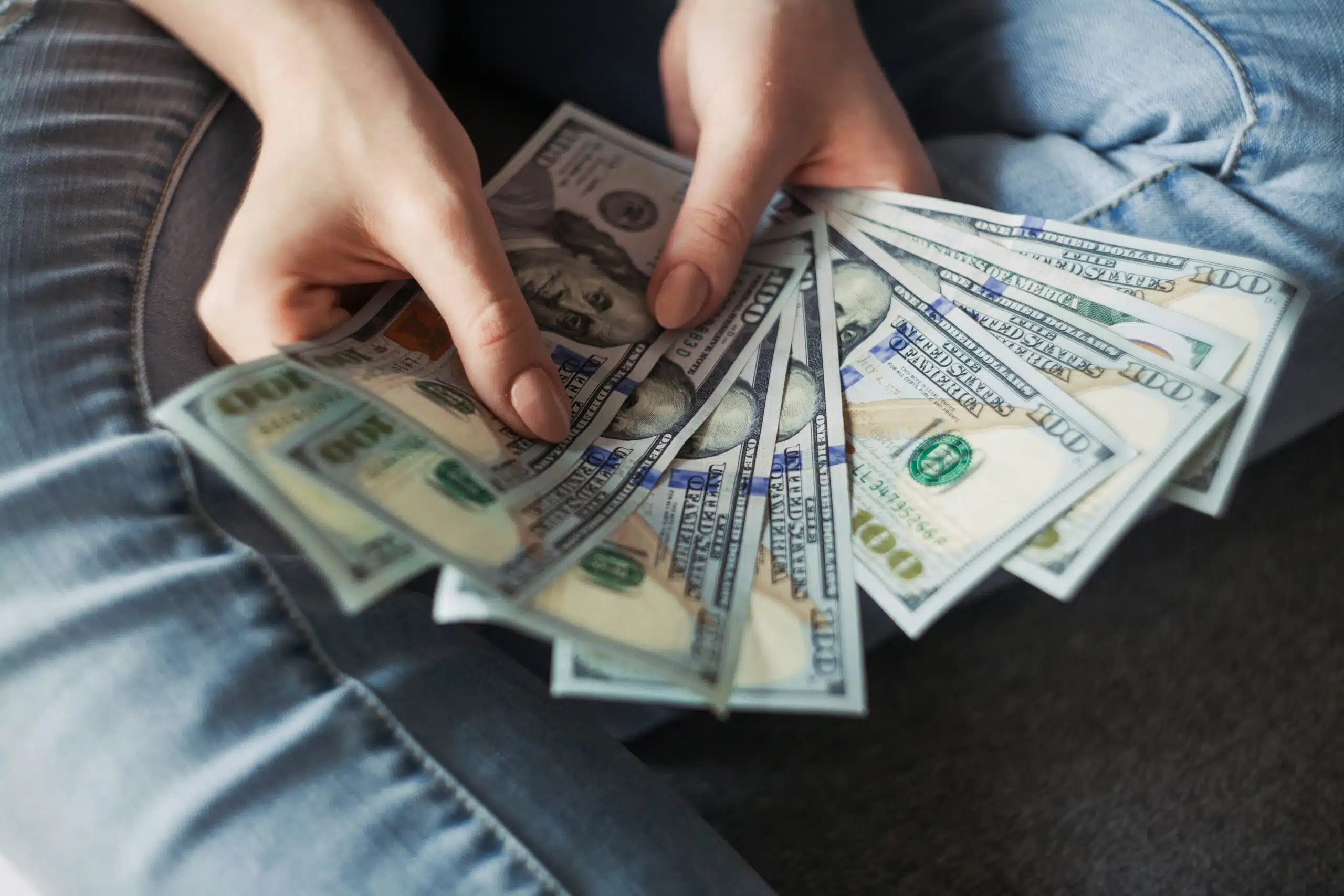 A person holding several $100 bills, representing the importance of budgeting for extra expenses beyond just the tent rental cost.