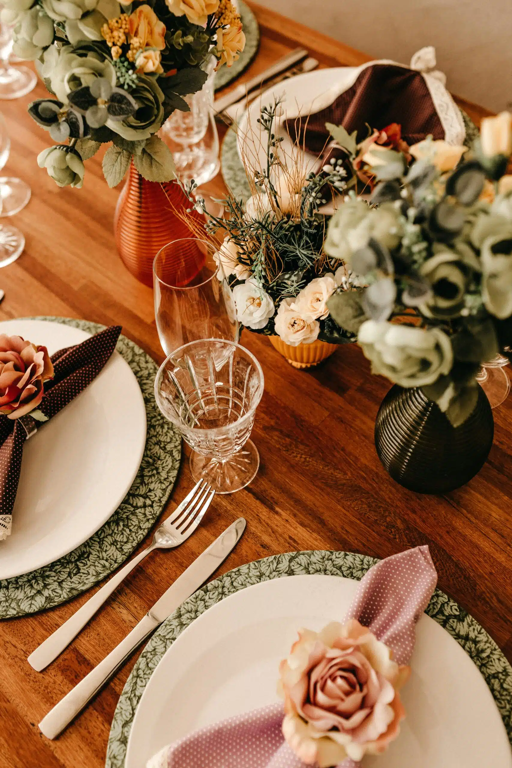 A beautifully decorated table featuring floral centerpieces, patterned chargers, and flower-accented napkin rings—perfect for adding charm to a themed wedding celebration.