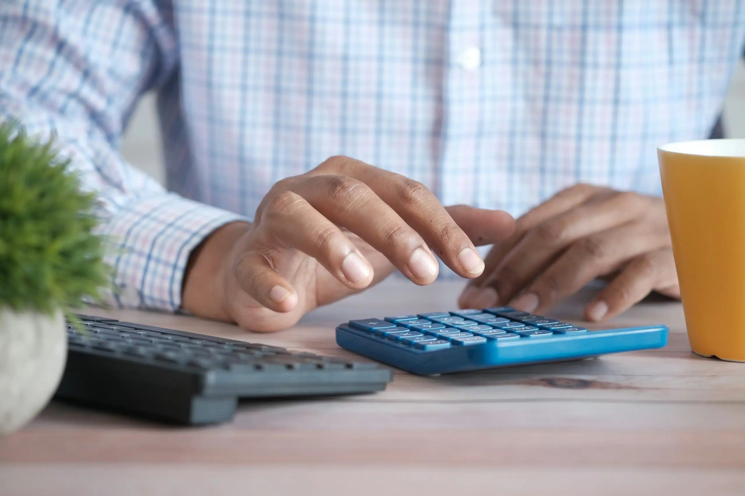 A person using a calculator at a desk, symbolizing the process of uncovering hidden fees and additional costs when budgeting for a party tent rental.