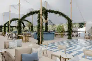 A stylish sailcloth lounge setup features cozy seating, lush greenery, and patterned flooring, ideal for creating inviting VIP and chillout zones at upscale festivals.