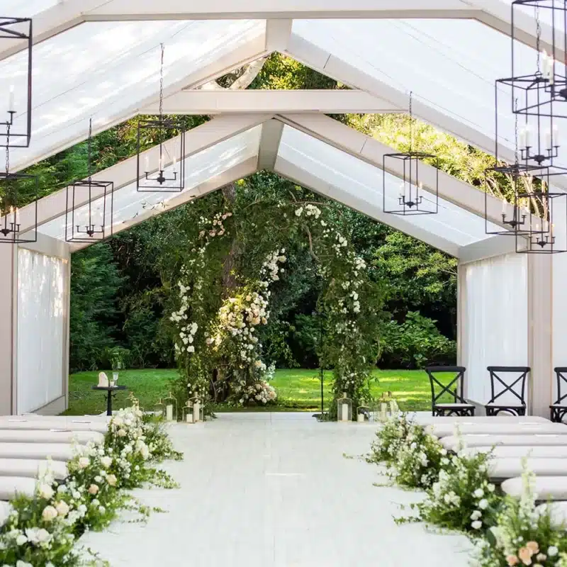 Wedding ceremony aisle inside a white-frame tent.