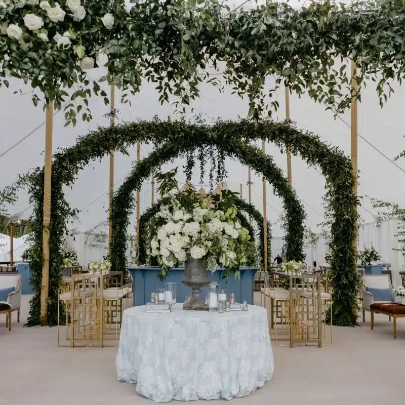 Elegant tent interior with floral arches and luxury wedding furniture rentals.