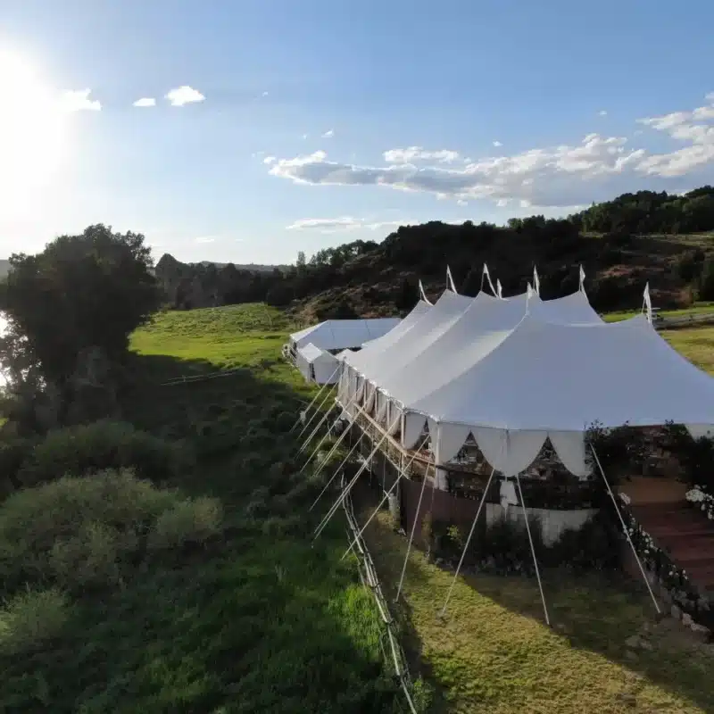 Scenic wedding tent perched near a river with surrounding greenery.