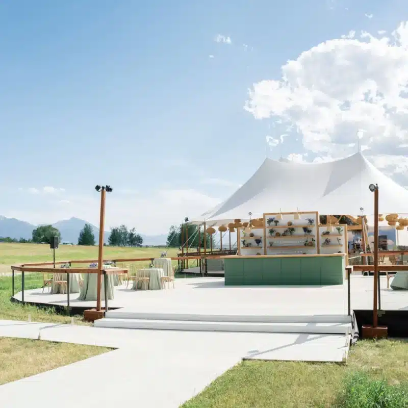 Outdoor cocktail area with minimalist lounge setup beside a Century Pole Tent and mountain views.