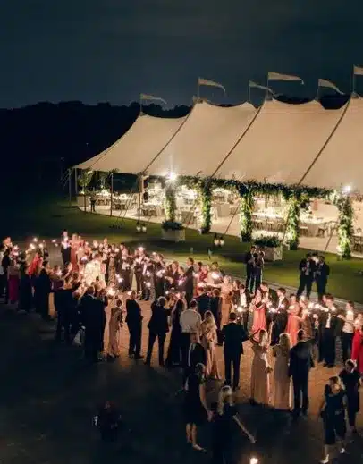Twinkle-lit wedding exit outside a greenery-draped Century Pole Tent showcasing how elegant lighting and thoughtful decor elevate commercial tent ambiance and guest experience.