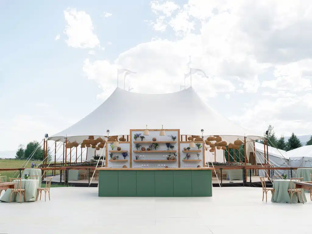 A bright sailcloth tent with open sides and natural wood framing, showcasing eco-conscious design features that reduce energy use and blend with the environment.