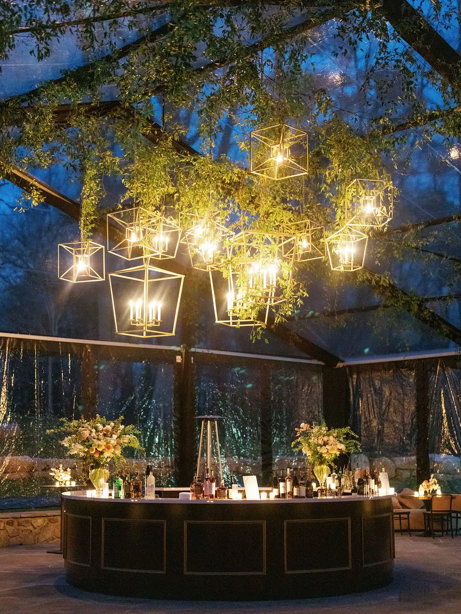 Clear span tent interior with hanging lights and decorated bar.