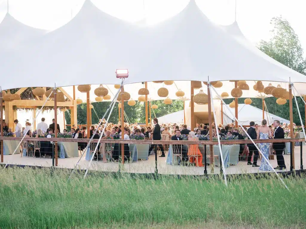 Guests dining inside a sailcloth tent with woven pendant lights