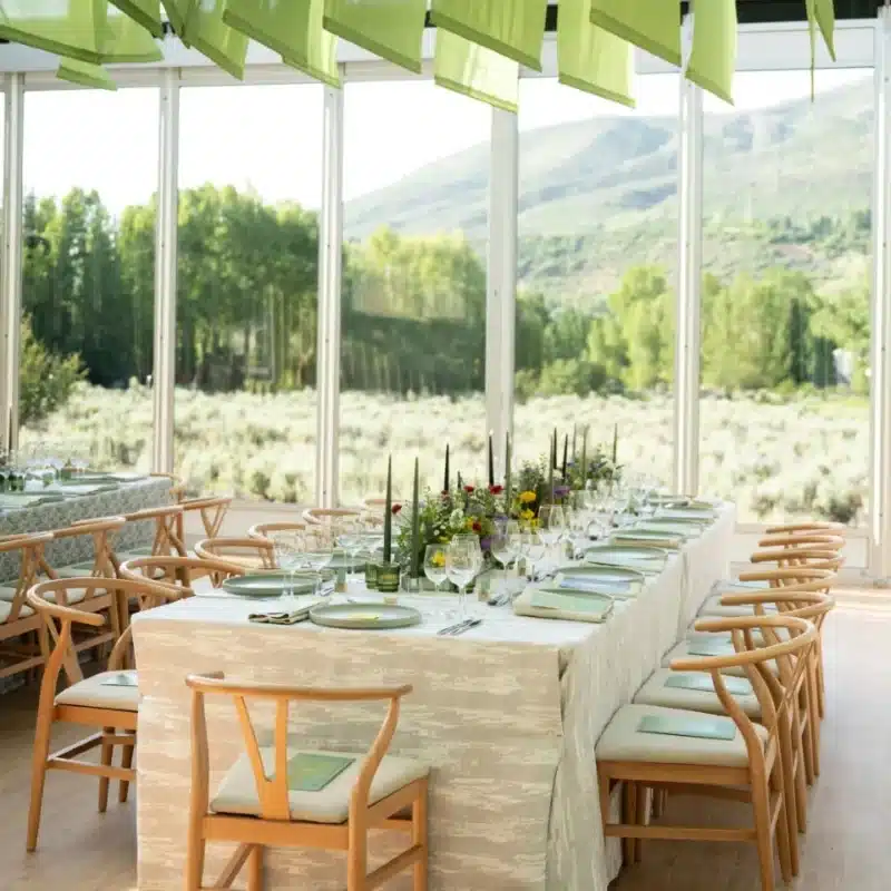 Corporate dinner setup inside clear tent with mountain views