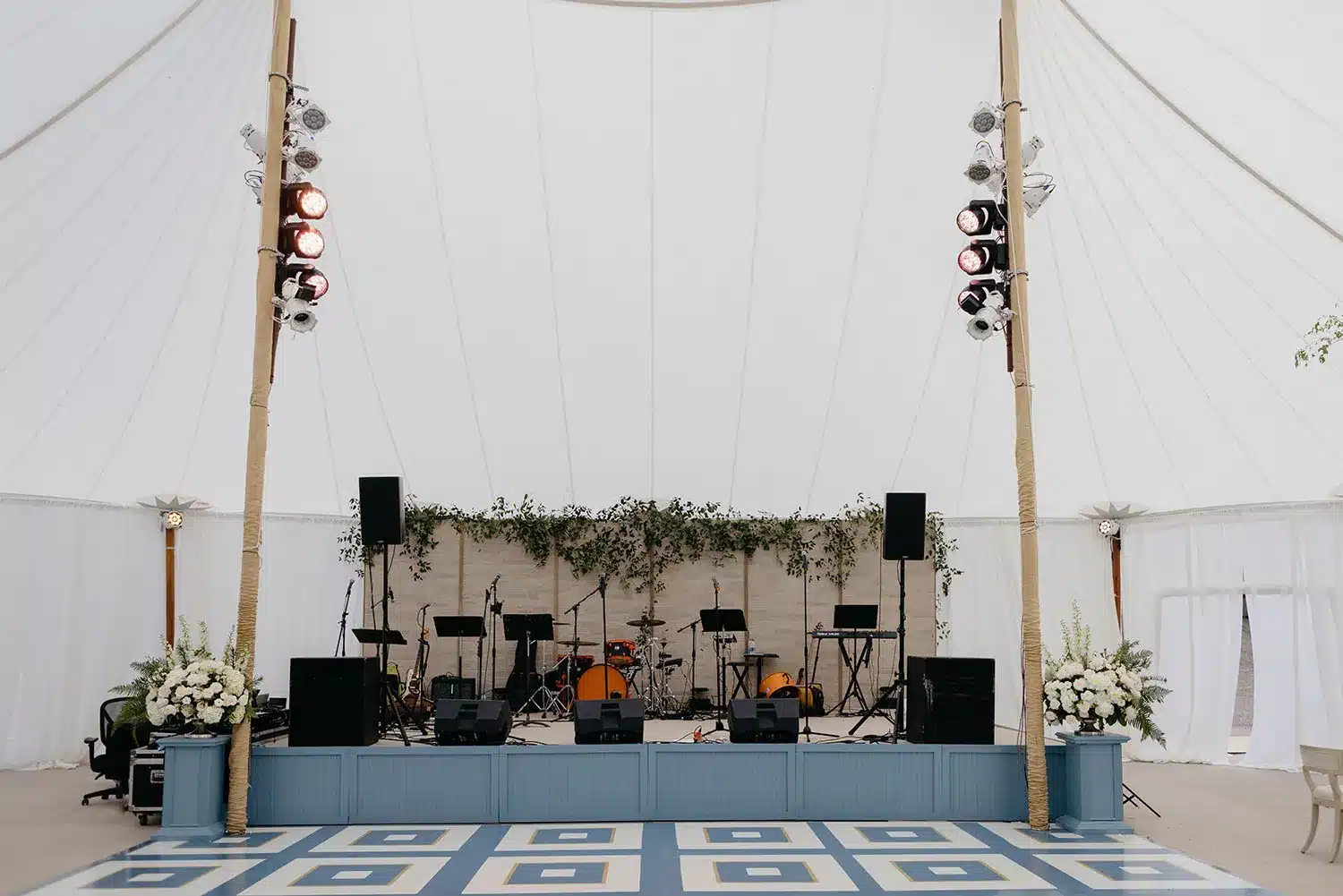 Century Pole Tent interior with elevated stage, audio equipment, and floral décor for live event setup.