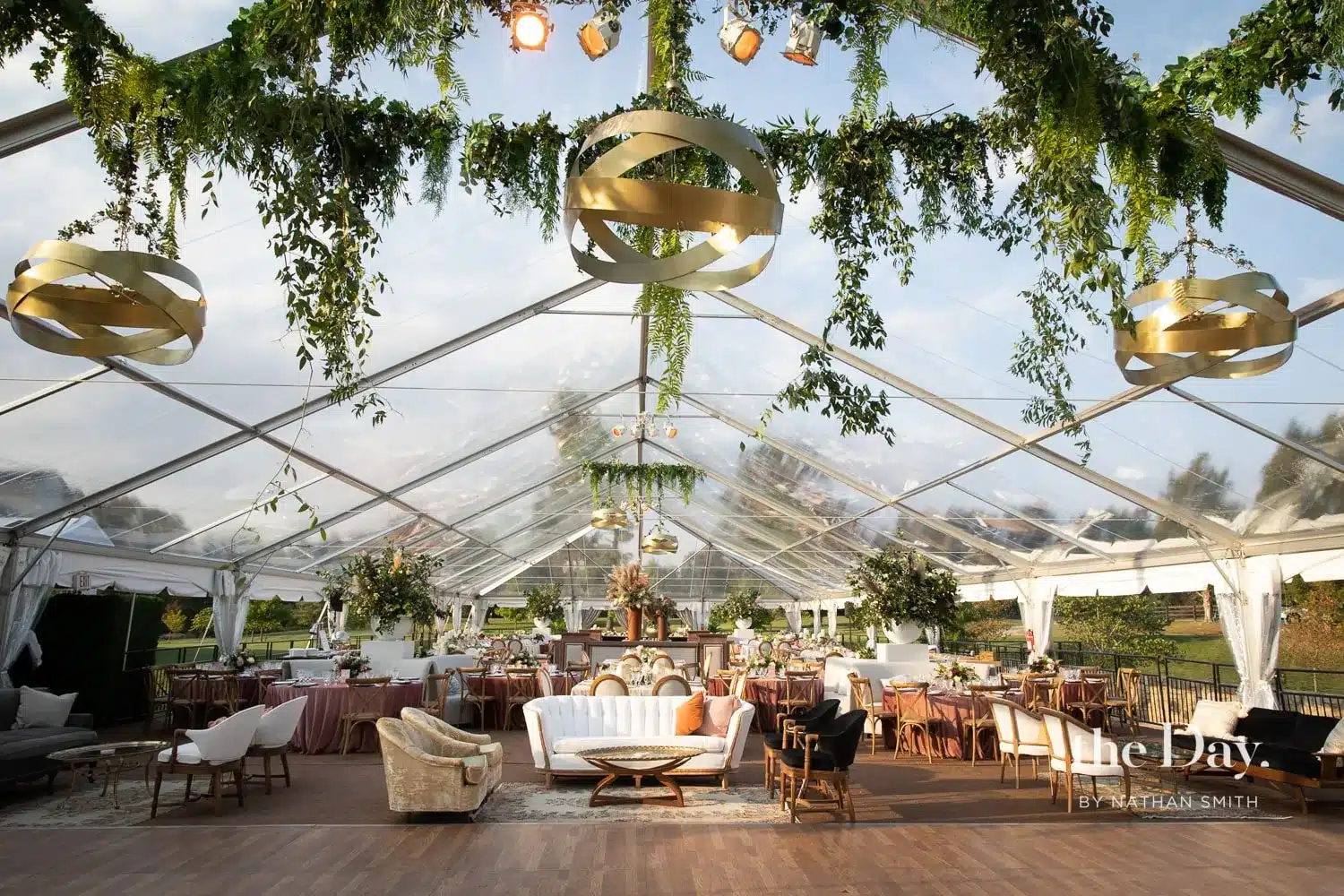 Interior of a clear span tent with lounge seating and hanging greenery.