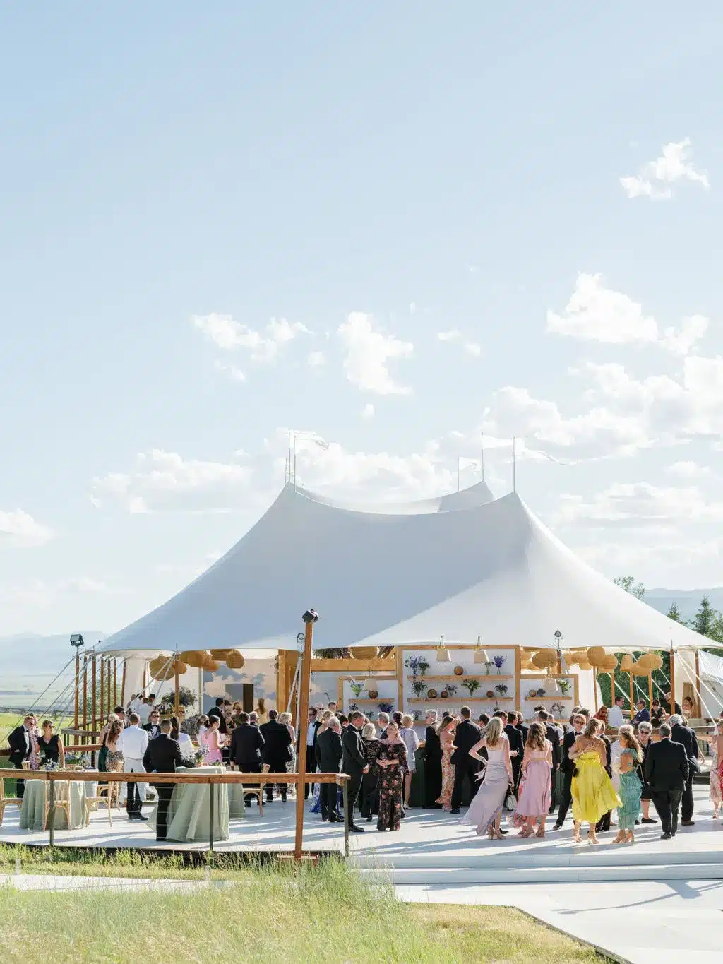 Guests mingling outside a tent at an outdoor wedding reception.