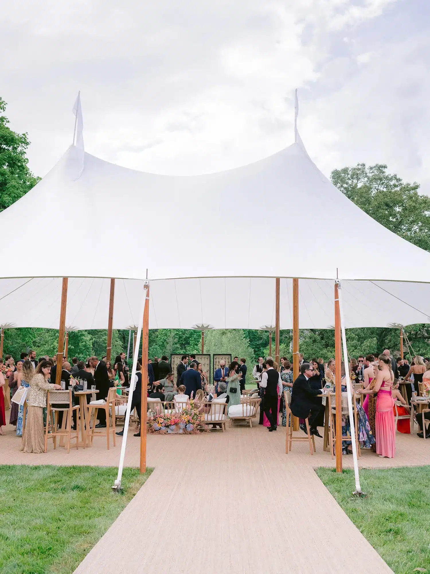 Open-sided high peak tent with guests at a daytime celebration.
