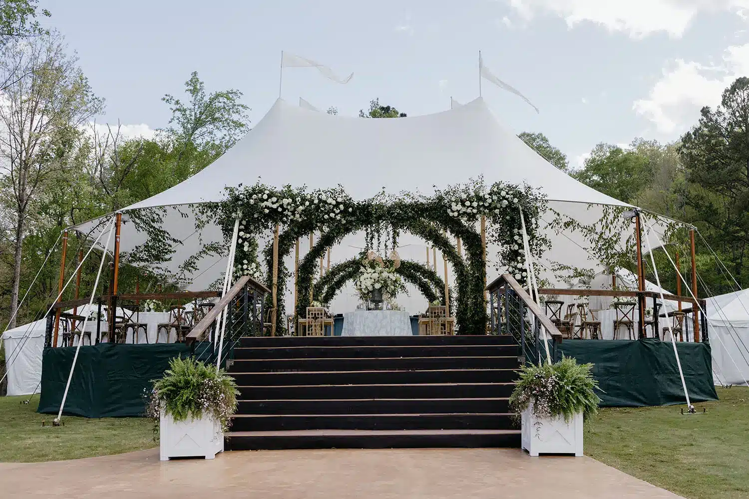 Decorated sailcloth tent with greenery arches and seating