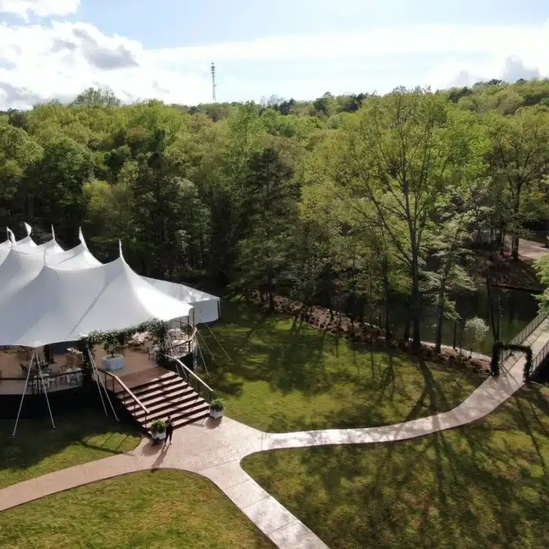 Sailcloth tent on elevated platform beside wooded pond