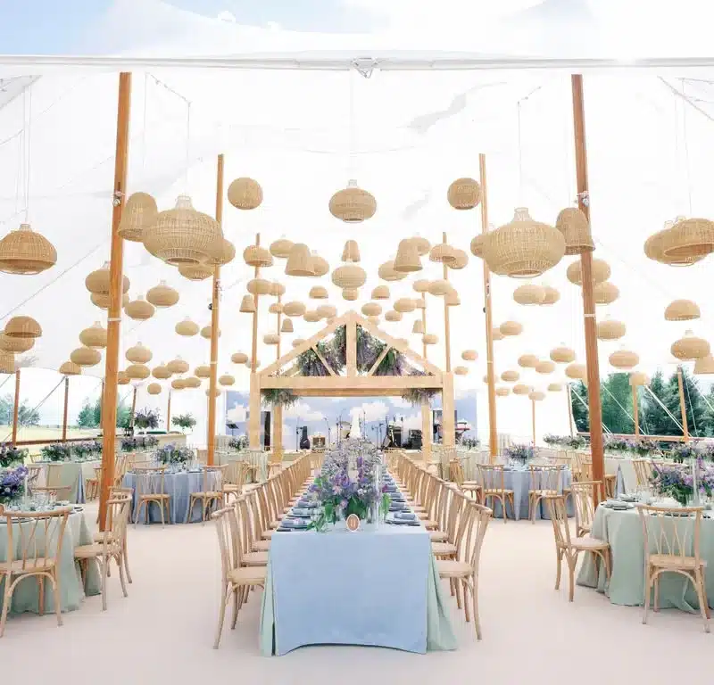 Tent dining design with hanging wicker lanterns and colorful tables