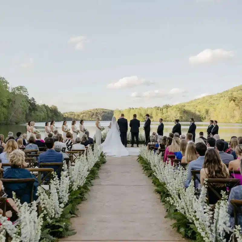 Scenic lakeside wedding ceremony with floral aisle décor