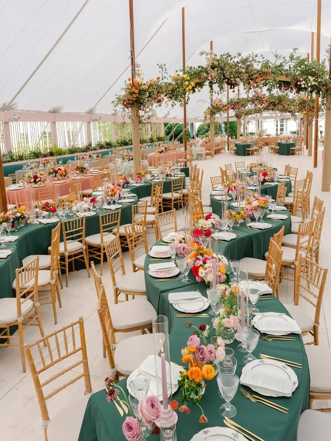 Vibrant floral reception setup under a white pole tent with open sides
