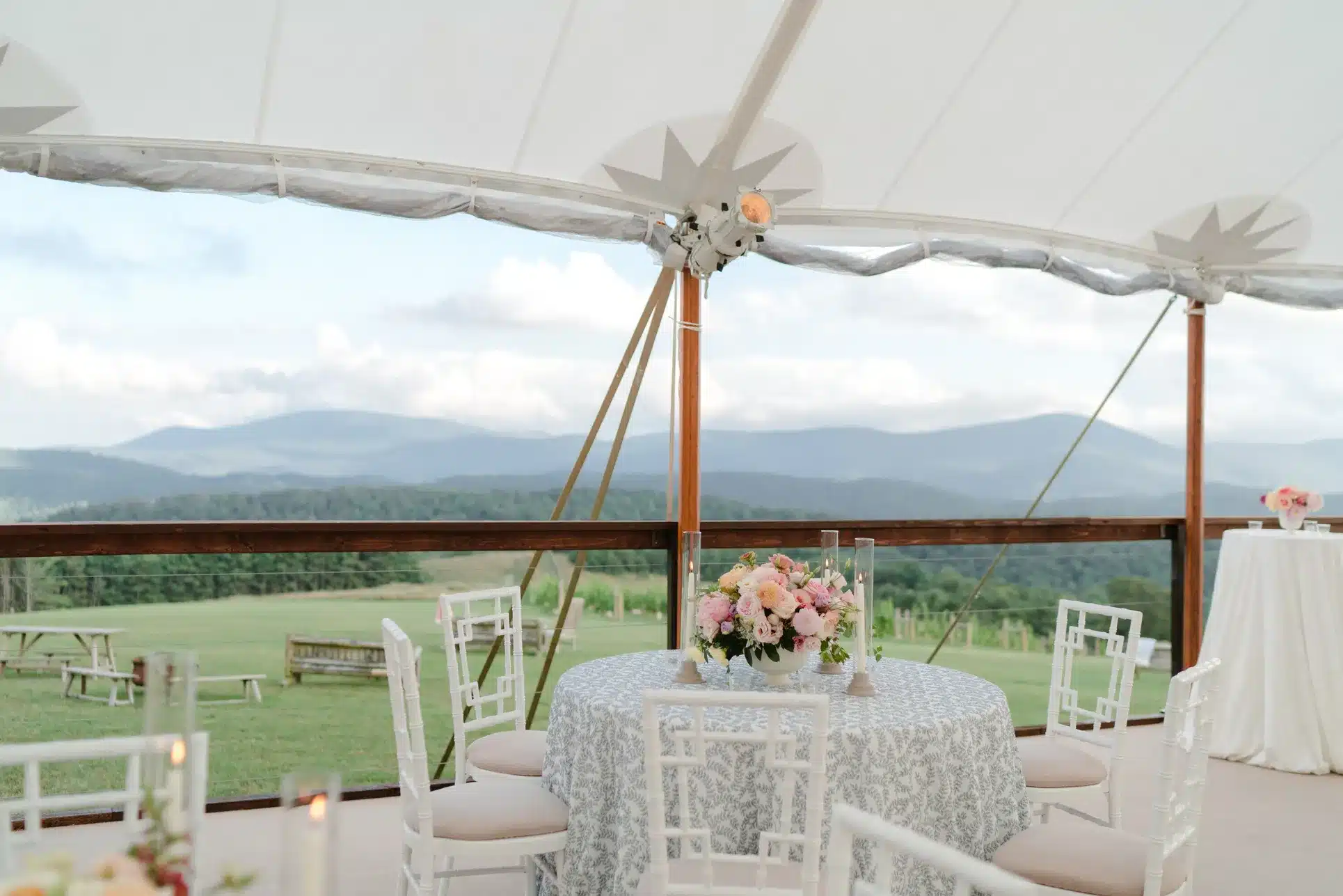 Round table with floral centerpiece under a sailcloth tent, overlooking a scenic mountain view—highlighting how elegant settings enhance corporate event ambiance.