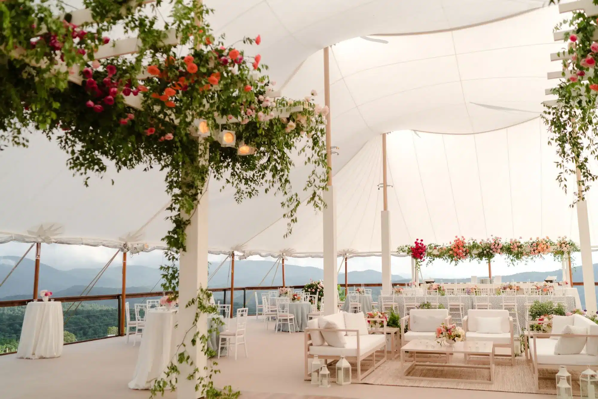Elegant tent interior with hanging floral arrangements and lounge seating