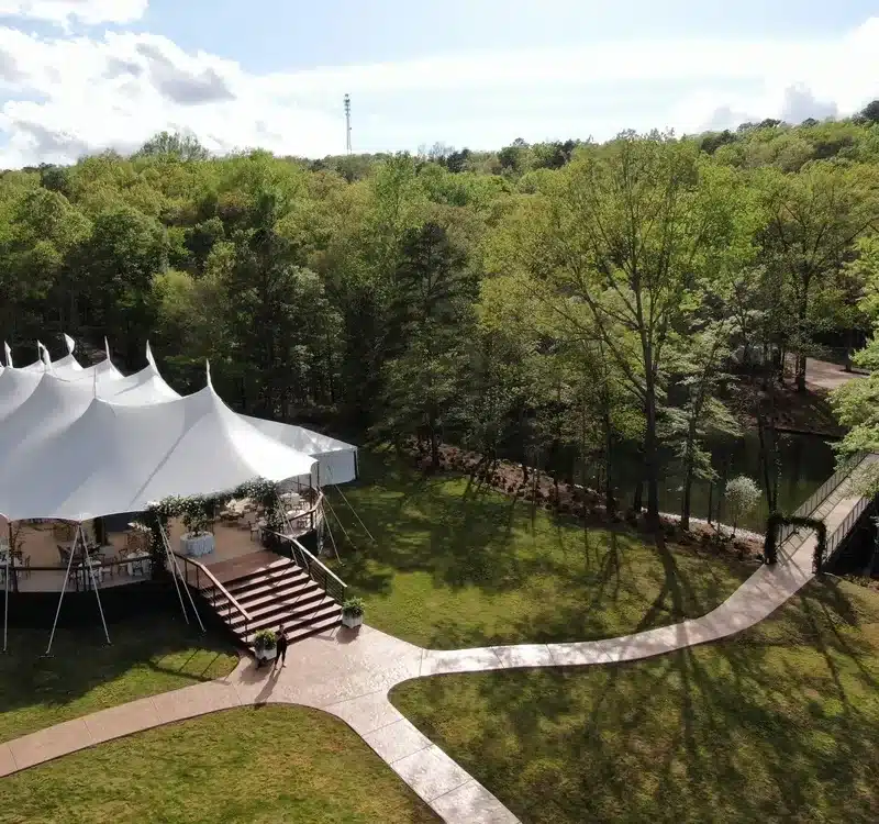A sailcloth tent surrounded by lush greenery, emphasizing the importance of storing tents clean, dry, and folded in a cool, ventilated space to prevent mildew and material stress.