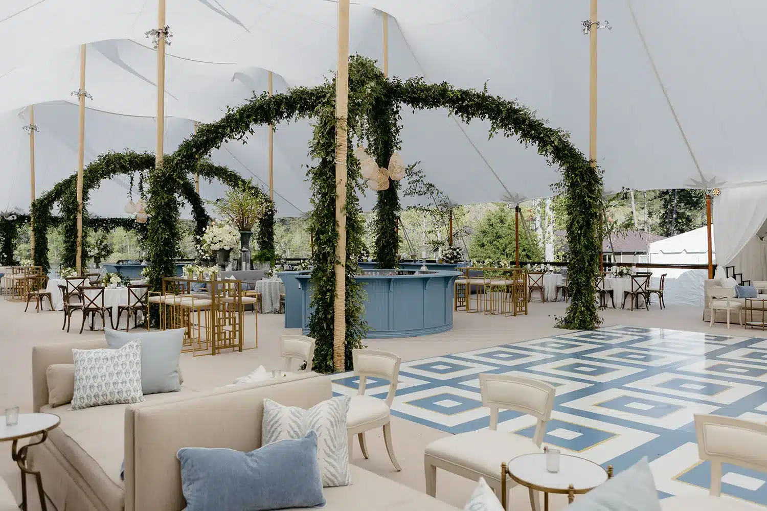 Patterned blue-and-white event floor with greenery arches and lounge seating