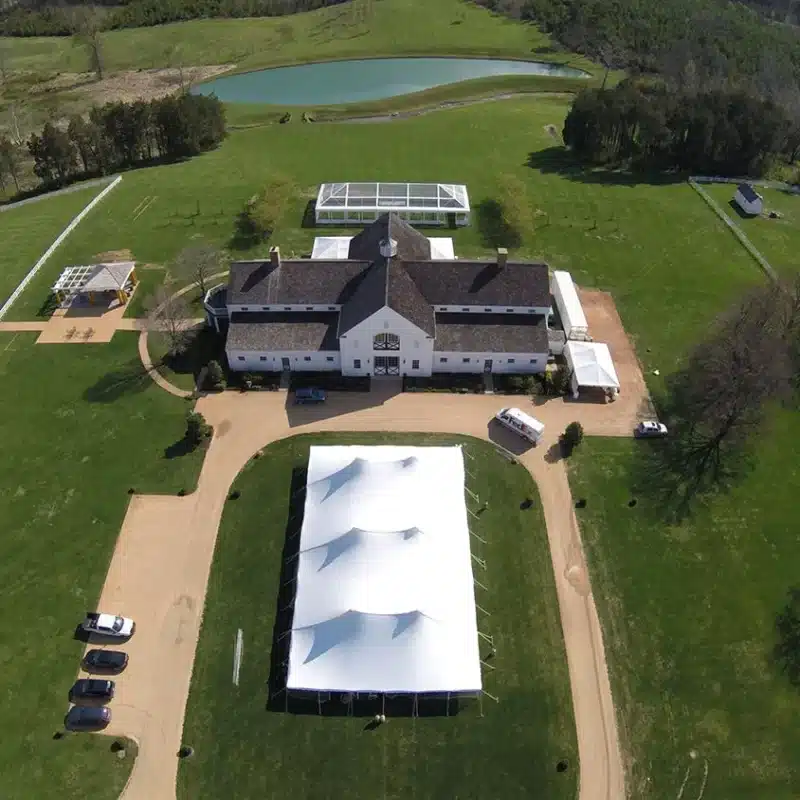 Estate grounds featuring a large white event tent set up beside a country-style venue