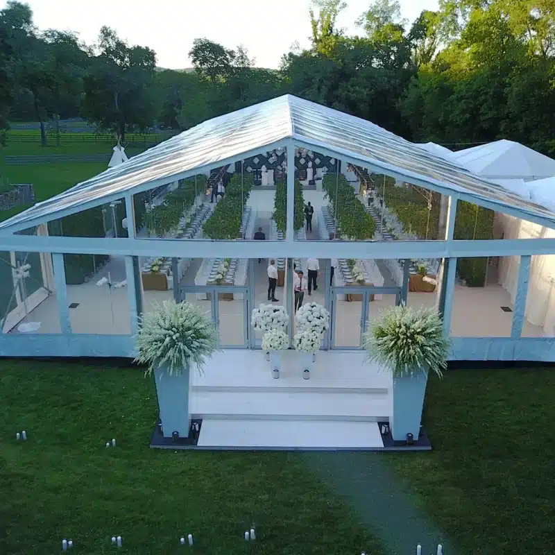 Clear-top white wedding tent with elegant floral entrance and long reception layout