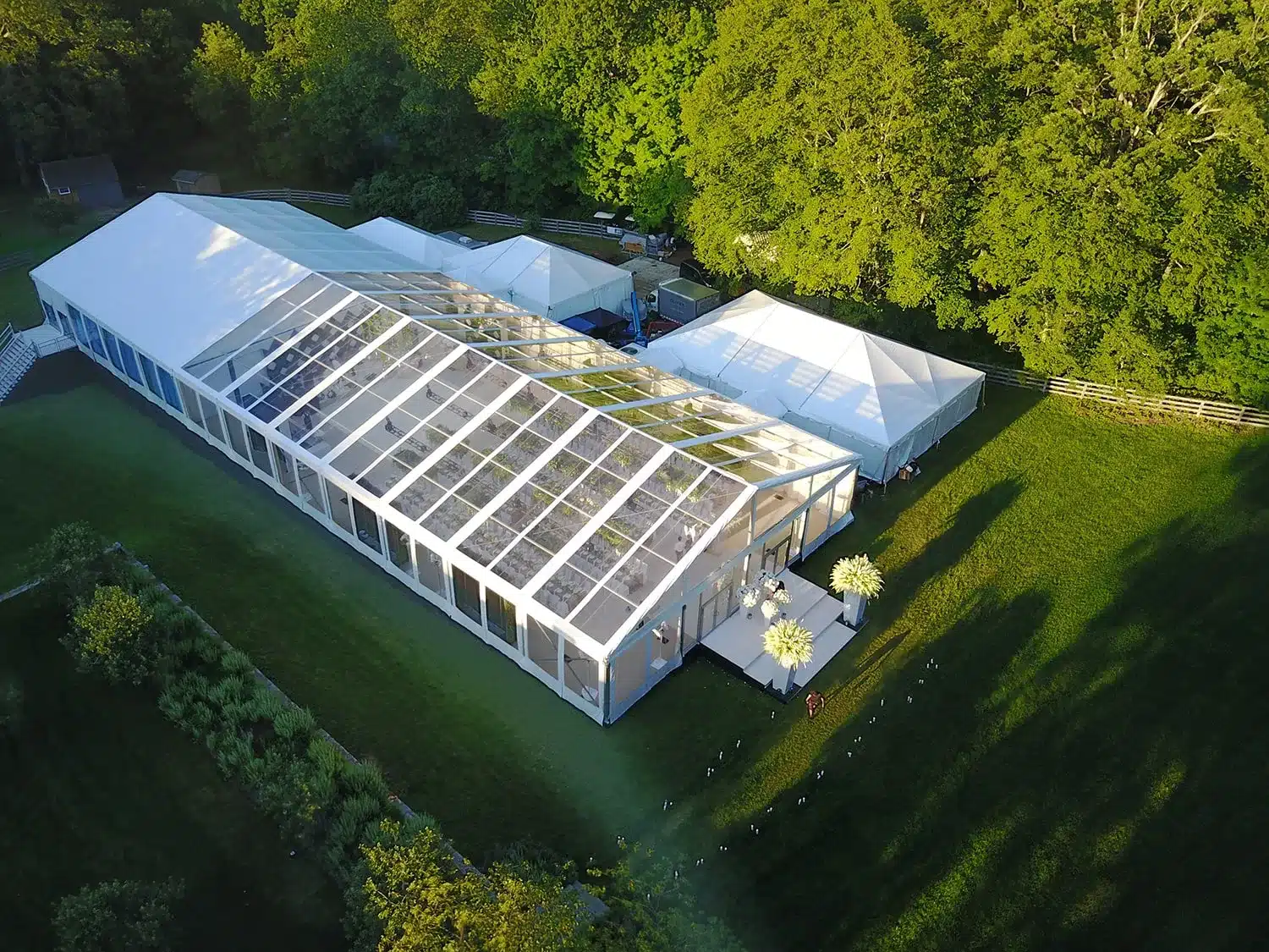 Aerial view of a large white wedding tent with clear roof panels on a private estate.