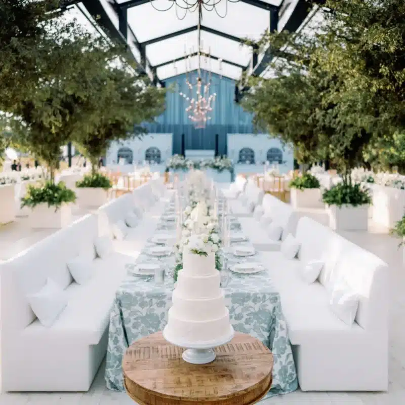 Elegant winter tent interior with long banquet tables, chandeliers, and lush greenery for a sophisticated lounge atmosphere.