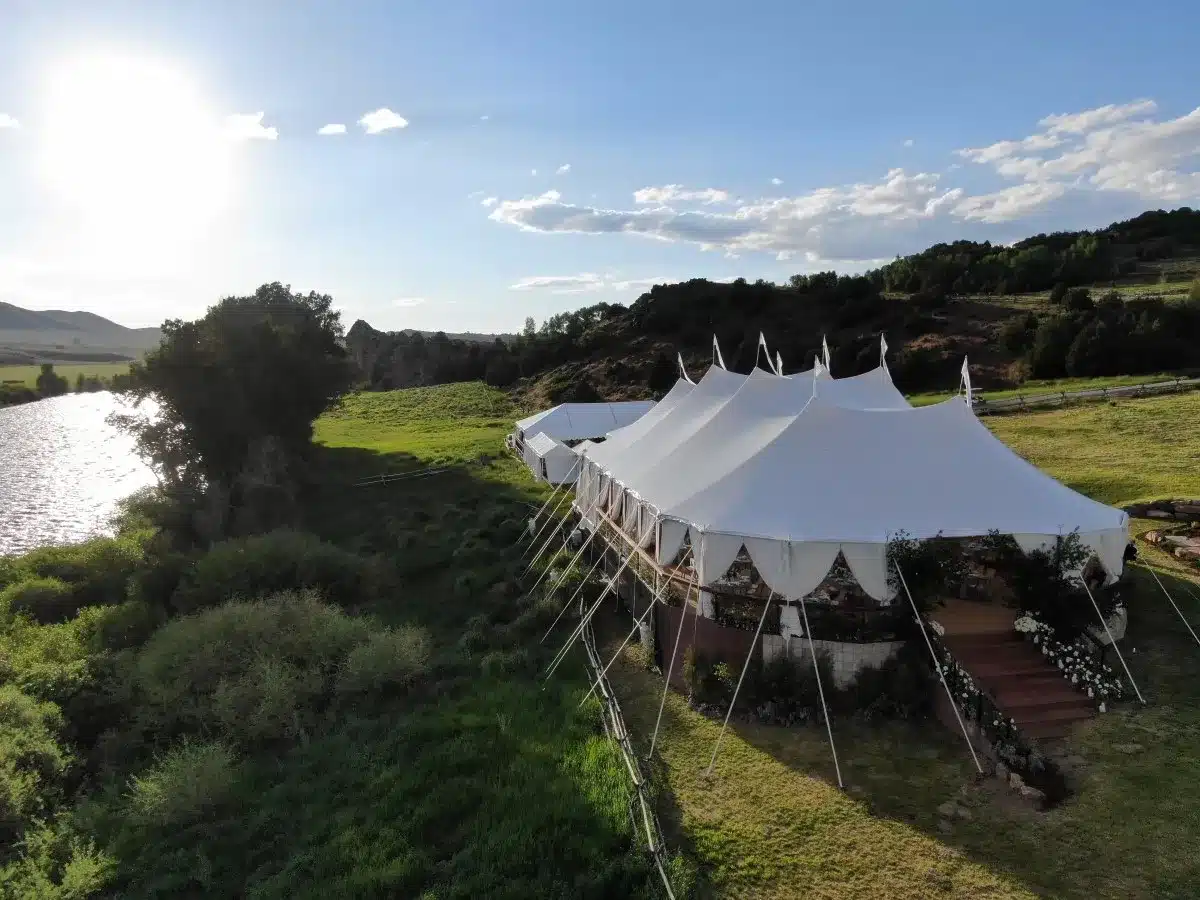 Large sailcloth tent overlooking a river and rolling landscape.