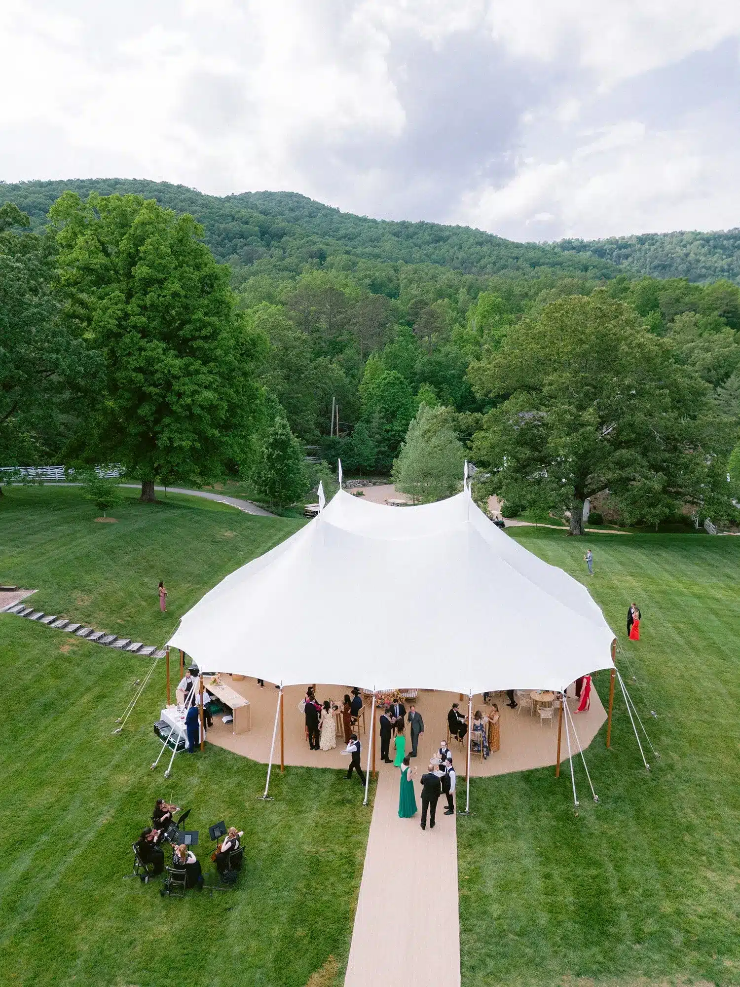Aerial view of guests gathered under a sailcloth tent at an outdoor wedding reception