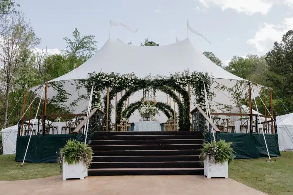 White backyard party tent with stairs and greenery décor, highlighting an elegant tent option for weddings and special events.
