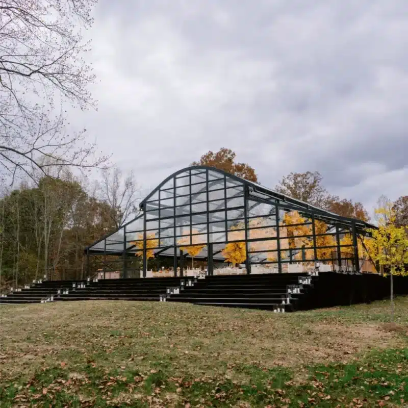 Glass wedding tent with autumn trees visible through the structure