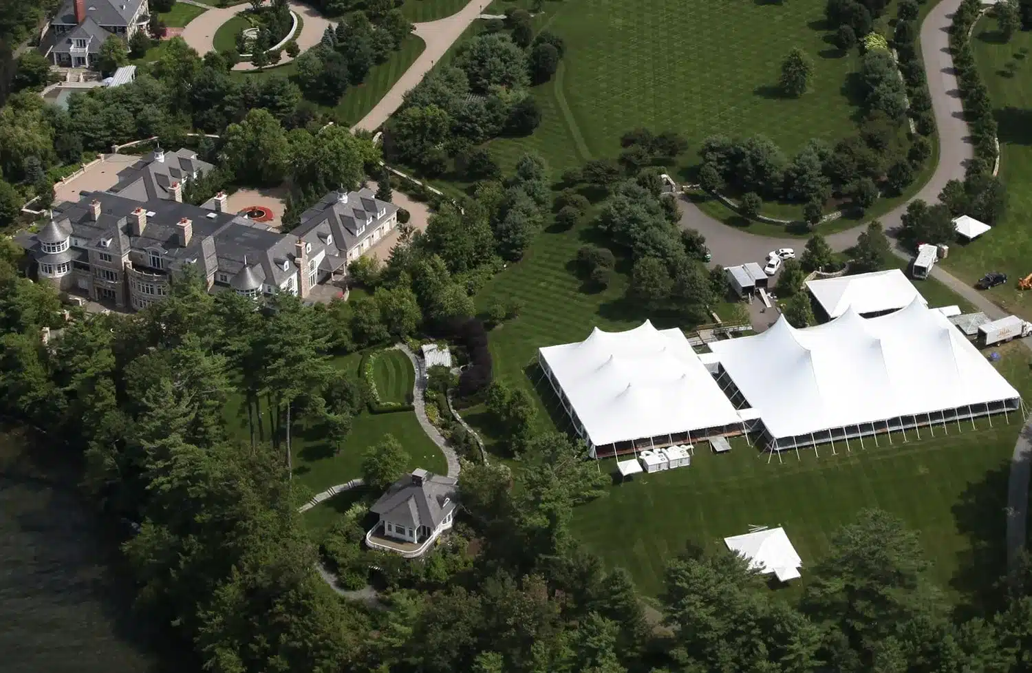 Aerial view of a private estate wedding featuring multiple white sailcloth tents set on manicured lawns.