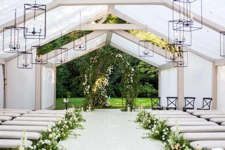Clear span tent with elegant chandeliers and string lights creating a romantic wedding ambiance