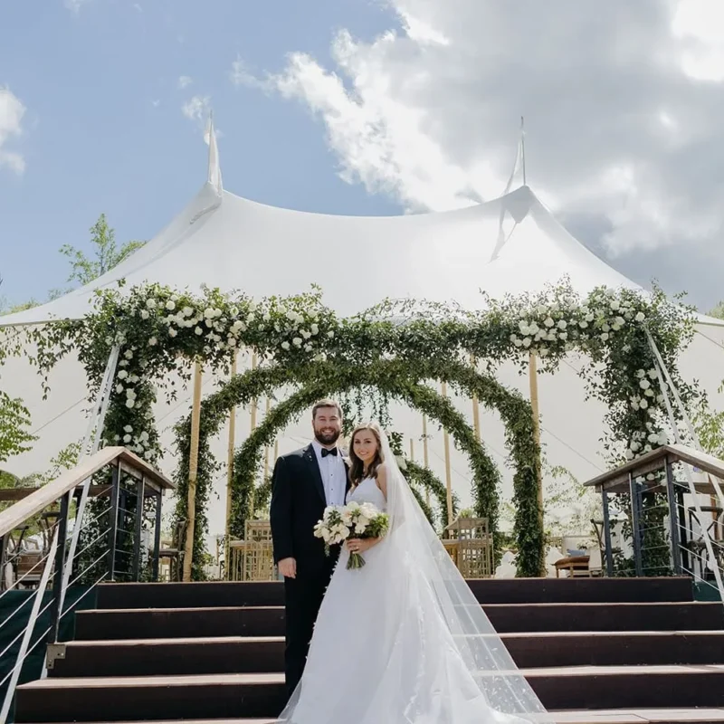 Open-air wedding tent with elevated entrance and greenery allowing airflow for a cool summer ceremony