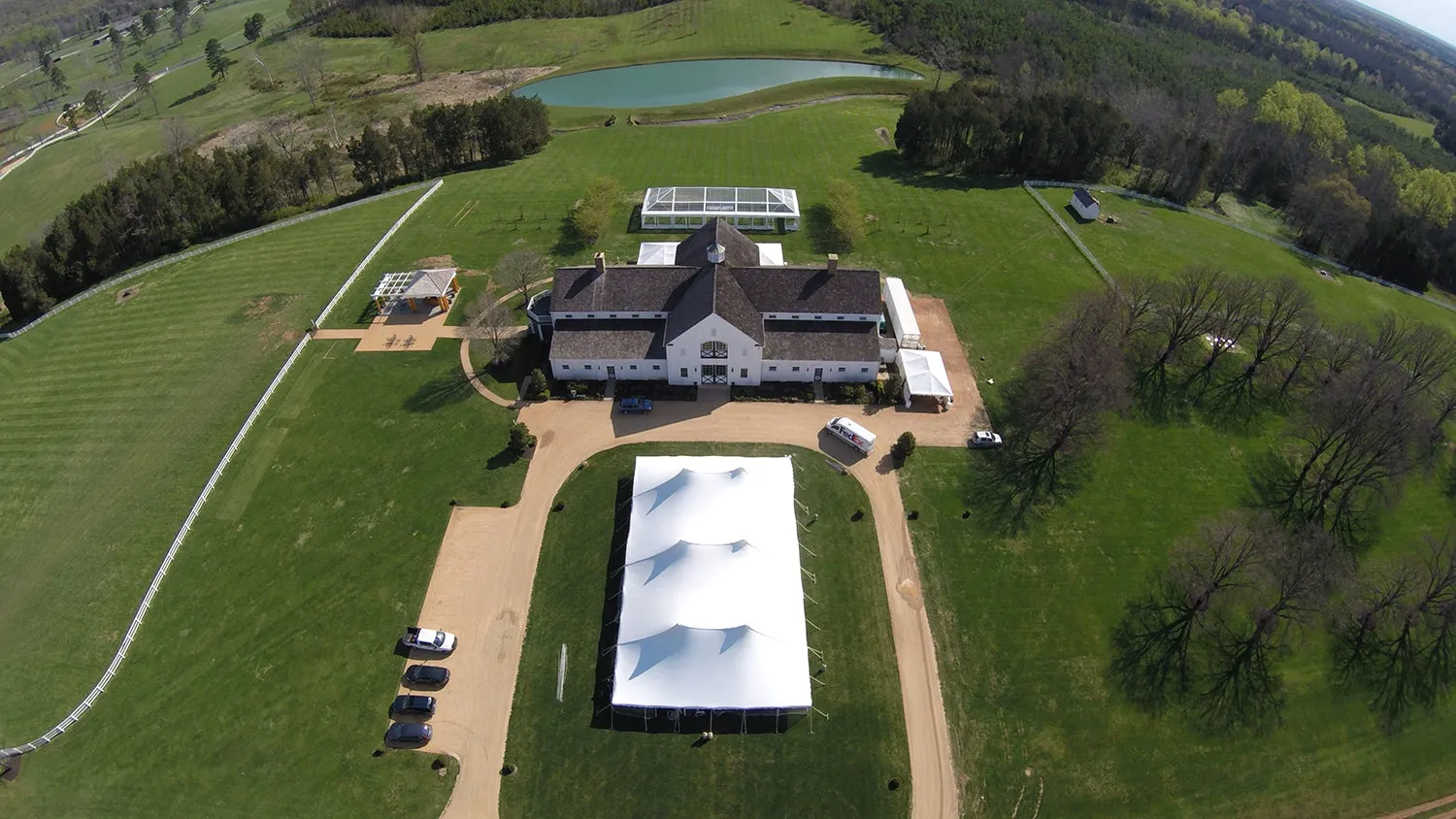 Aerial view of countryside wedding venue with large reception tent showing guest arrival path and entrance layout