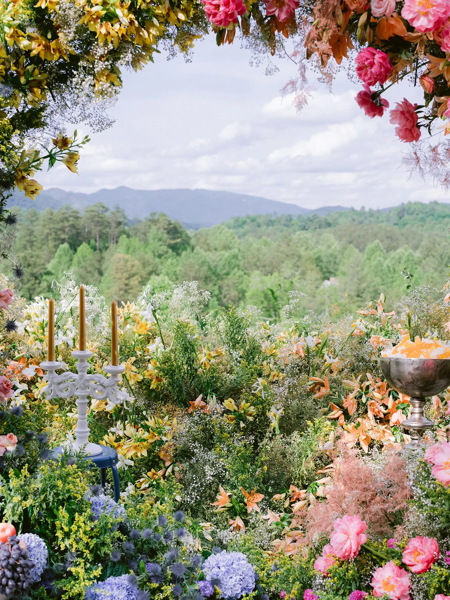 Floral garden installation with candles and greenery used to create a romantic entrance pathway to a summer wedding tent