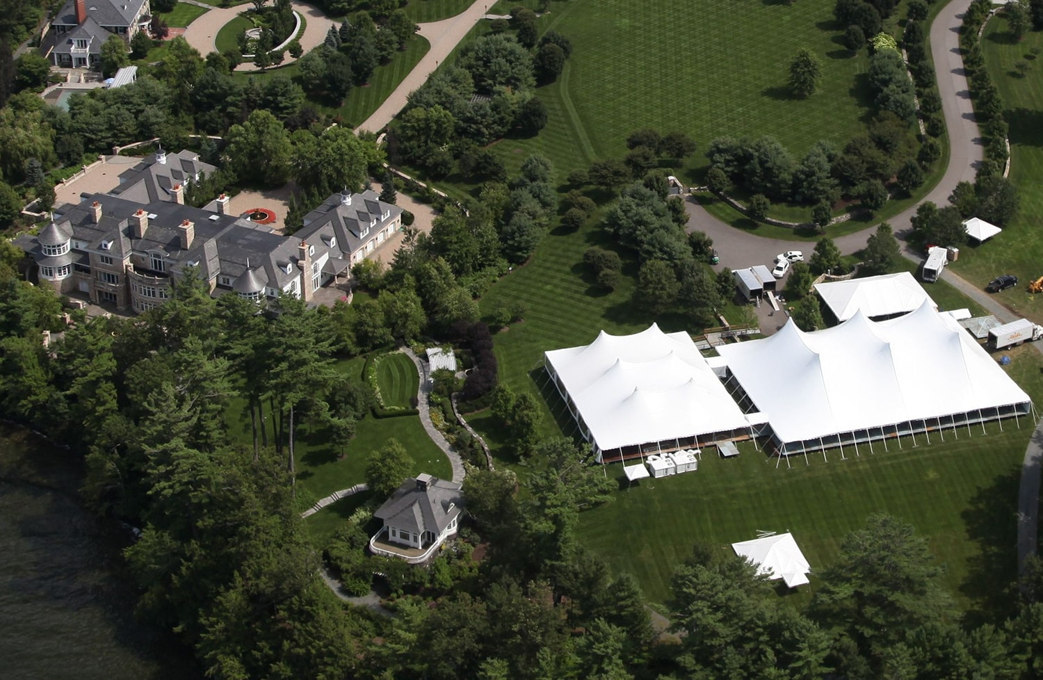 Aerial view of estate wedding venue with large sailcloth tents on manicured grounds.