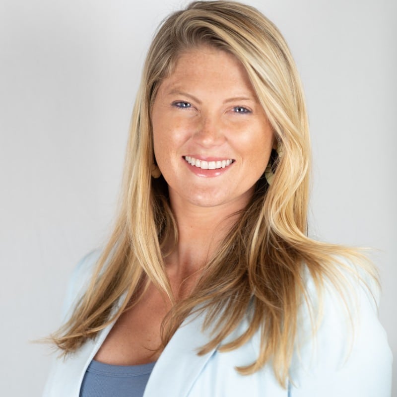 Mary Kathryn McConaghy, Managing Director at Curated Events, smiling with blonde hair and a light blue blazer, representing expertise in event management and lighting solutions for winter weddings.